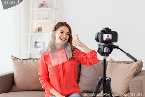 Image of woman with camera recording video at home