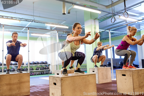 Image of group of people doing box jumps exercise in gym