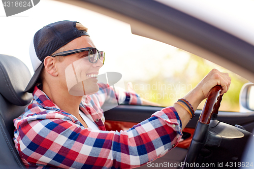 Image of happy young man in shades driving convertible car