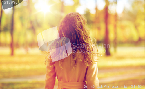 Image of beautiful young woman walking in autumn park