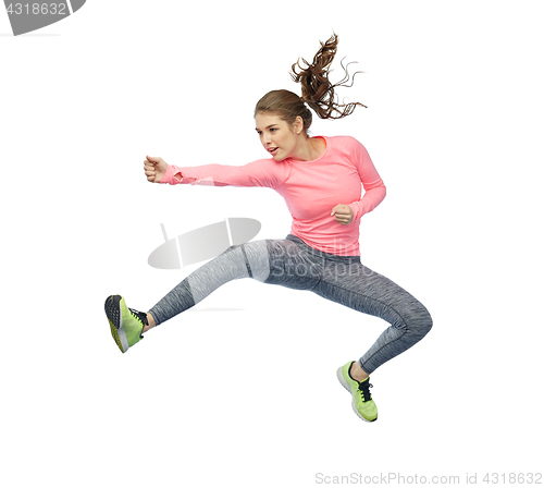 Image of happy sporty young woman jumping in fighting pose