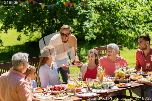 Image of happy family having dinner or summer garden party