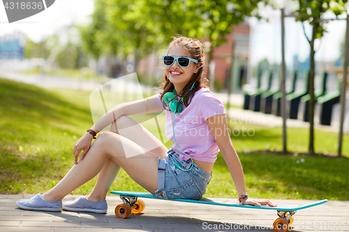 Image of happy teenage girl with headphones and longboard