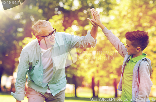 Image of old man and boy making high five at summer park