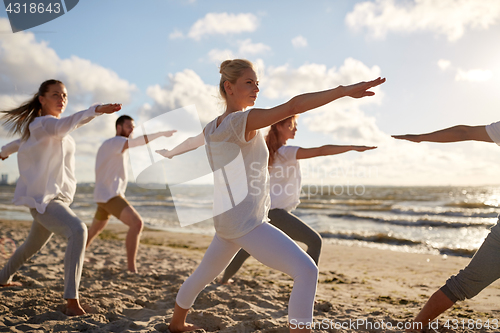 Image of group of people making yoga exercises on beach