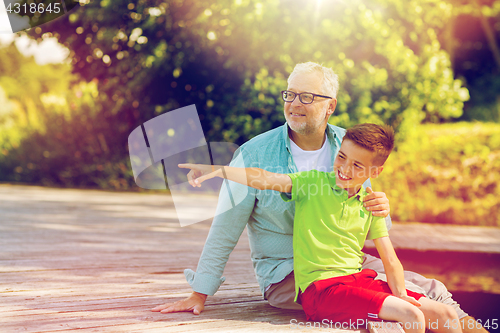 Image of grandfather and grandson sitting on river berth