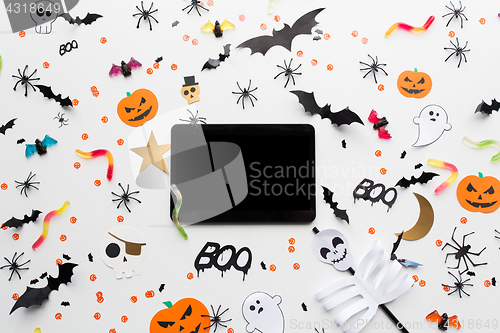 Image of tablet pc, halloween party decorations and candies