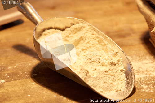 Image of flour in bakery scoop on wooden kitchen table