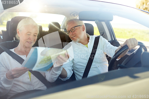 Image of happy senior couple with map driving in car