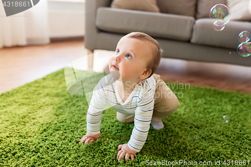 Image of baby boy playing with soap bubbles at home