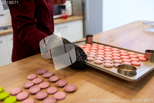 Image of chef with macarons on oven tray at confectionery