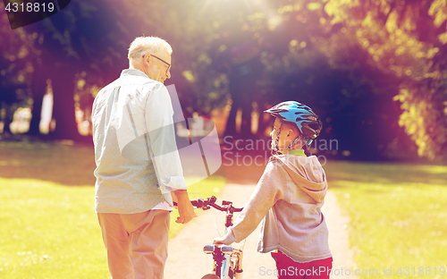 Image of grandfather and boy with bicycle at summer park