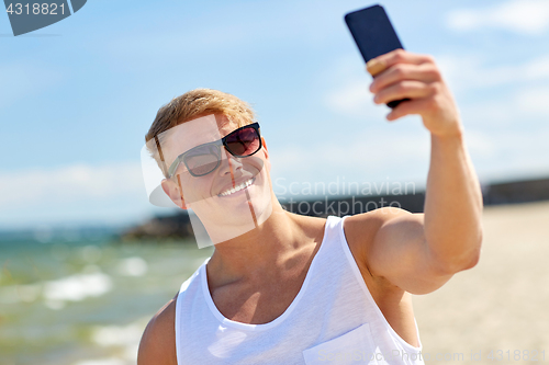 Image of man taking selfie by smartphone on summer beach