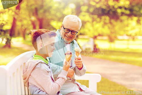 Image of old man and boy eating ice cream at summer park