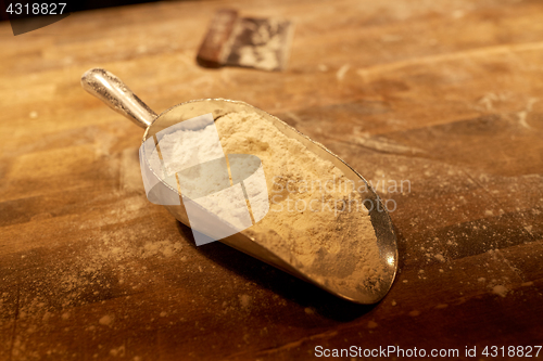 Image of flour in bakery scoop and dough cutter on table