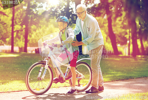 Image of grandfather and boy with bicycle at summer park