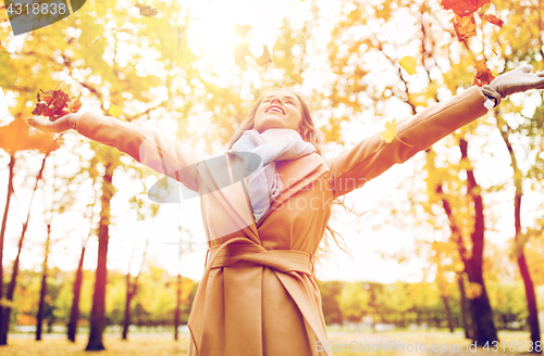 Image of happy woman having fun with leaves in autumn park