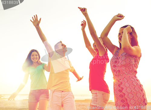 Image of smiling friends dancing on summer beach