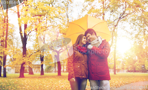 Image of smiling couple with umbrella in autumn park