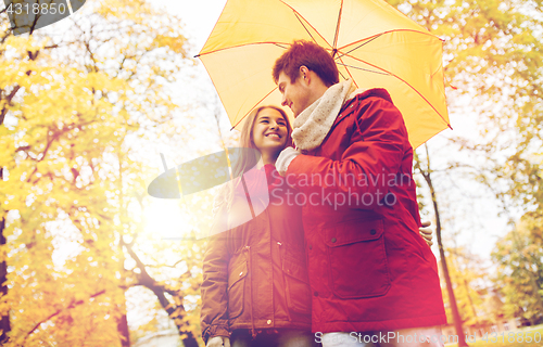 Image of smiling couple with umbrella in autumn park