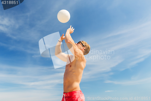 Image of young man with ball playing volleyball on beach