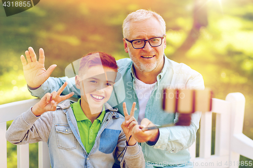 Image of old man and boy taking selfie by smartphone