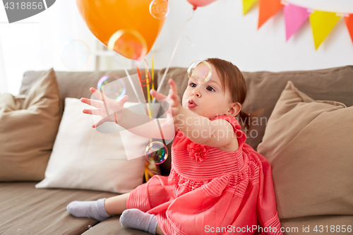 Image of baby girl with soap bubbles on birthday party