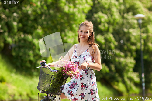 Image of happy woman riding fixie bicycle in summer park