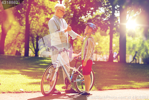 Image of grandfather and boy with bicycle at summer park