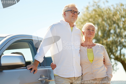 Image of happy senior couple hugging at car in summer