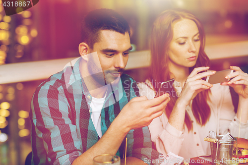 Image of couple with smartphones dining at restaurant