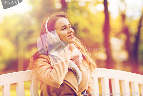 Image of happy woman with headphones in autumn park