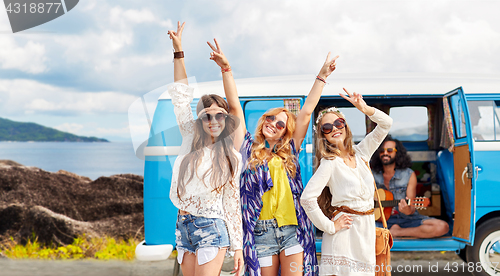 Image of happy hippie friends at minivan car on island