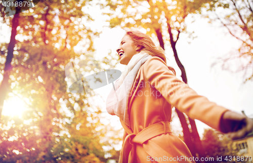 Image of beautiful happy young woman walking in autumn park