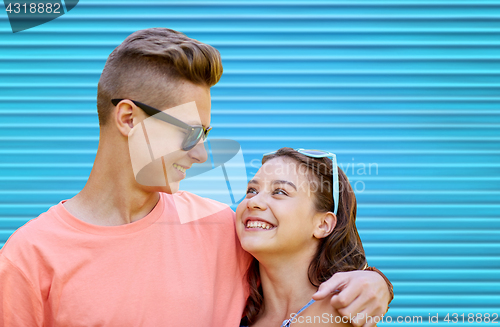 Image of happy teenage couple hugging over blue background
