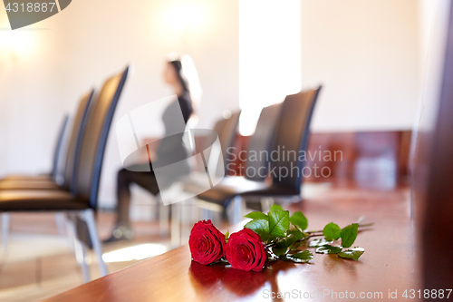 Image of red roses and woman crying at funeral in church