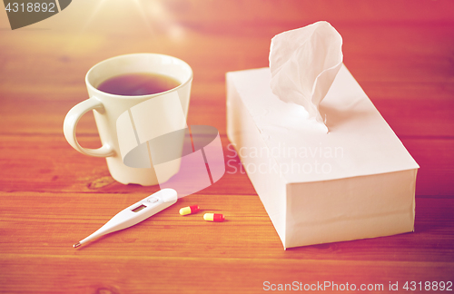 Image of cup of tea, paper wipes and thermometer with pills