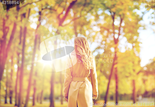 Image of beautiful young woman walking in autumn park