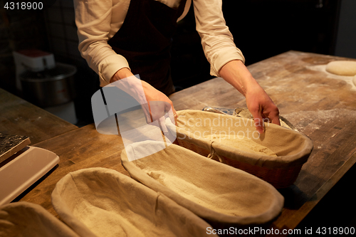 Image of baker with dough rising in baskets at bakery