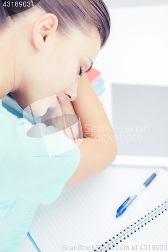 Image of tired student sleeping on stock of books