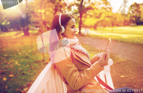 Image of woman with tablet pc and headphones in autumn park