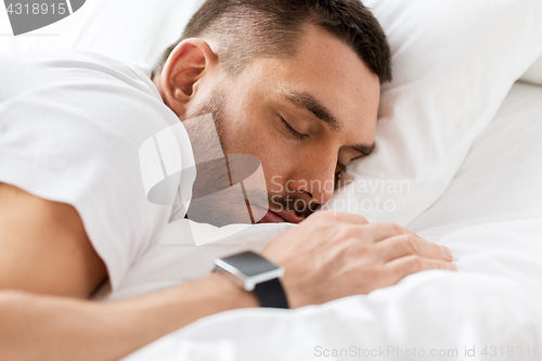 Image of close up of man with smartwatch sleeping in bed