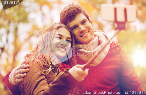 Image of couple taking selfie by smartphone in autumn park