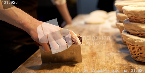 Image of baker portioning dough with bench cutter at bakery