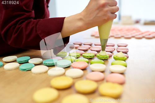 Image of chef with injector squeezing filling to macarons