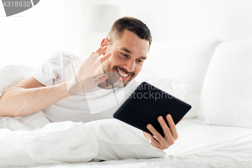 Image of man with tablet pc having video call in bed