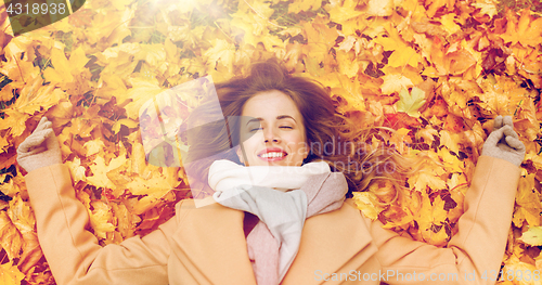 Image of beautiful happy woman lying on autumn leaves