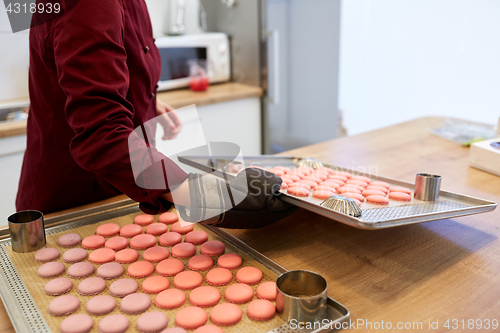 Image of chef with macarons on oven tray at confectionery