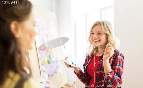 Image of student girls with easel painting at art school