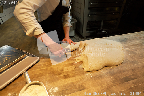 Image of baker portioning dough with bench cutter at bakery